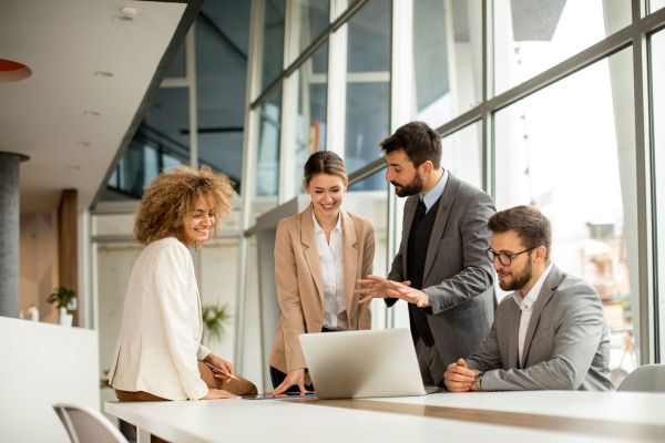 a group of people standing around a table looking at a laptop