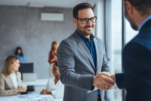 a person in a suit shaking hands with another person in a room